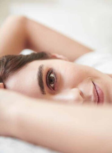 Close up portrait of beautiful young woman lying on bed